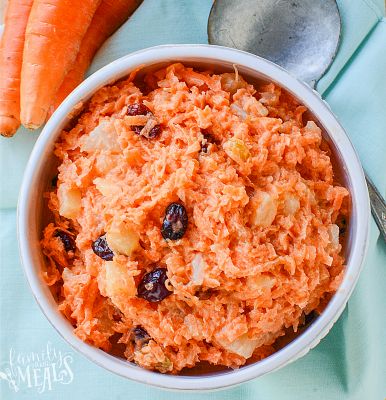 carrots and raisins in a white bowl on a blue cloth