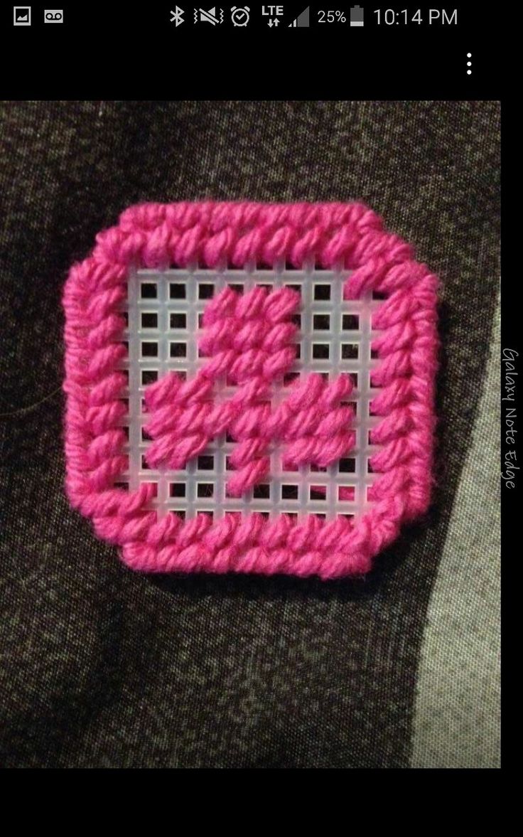 a close up of a pink and white crocheted object on a person's lap