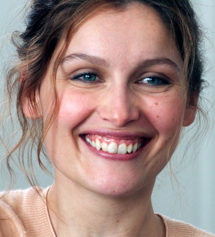 a smiling woman with blue eyes and brown hair wearing a beige sweater smiles at the camera