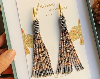 a pair of tasseled earrings sitting on top of a card