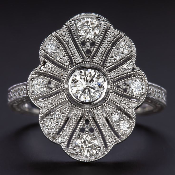 an antique style diamond ring with filigrees in the center and shoulders, on a black background