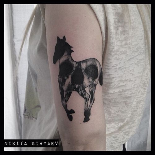 a black and white horse tattoo on the left upper half of the arm is shown