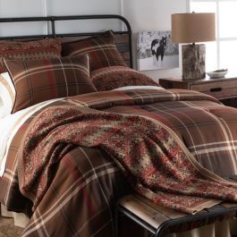 a bed with plaid comforter and pillows in a bedroom