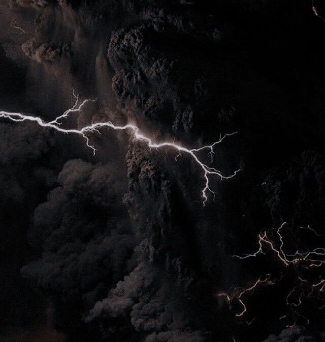 lightning strikes through the dark clouds above a mountain range in this aerial photo taken from space