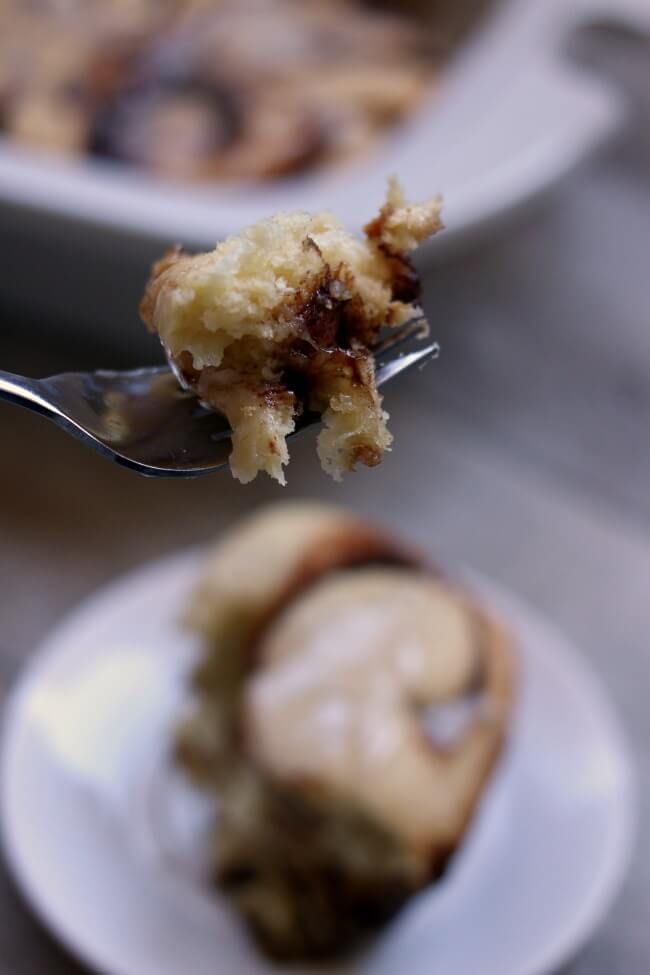 a piece of cake on a plate with a fork in the foreground and another half eaten dessert in the background