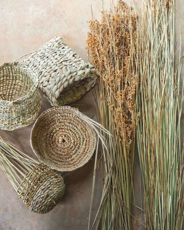 three woven baskets and some grass on the ground