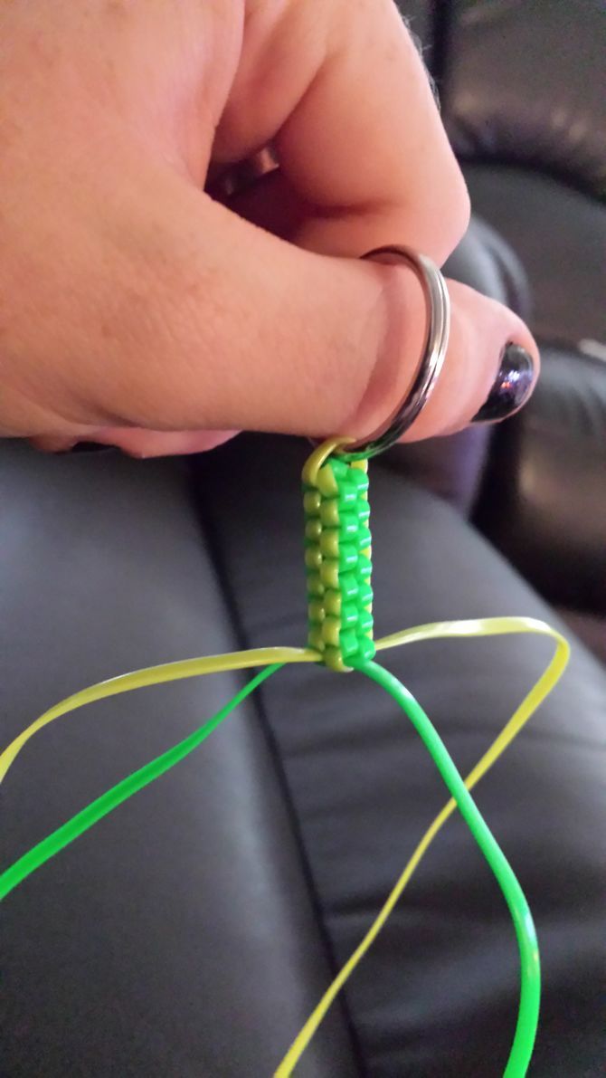 a person is holding the end of a green and yellow cord on a black leather couch