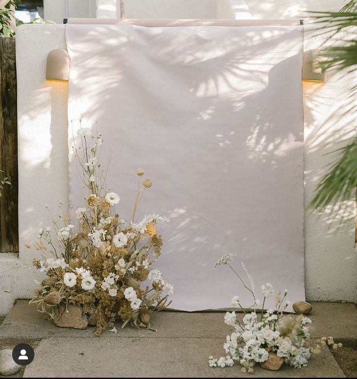 white flowers are sitting on the ground next to a large piece of paper that has been placed in front of it