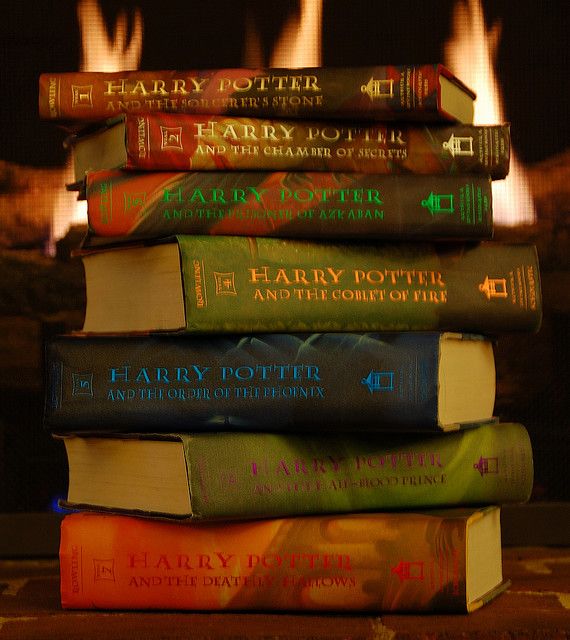 a stack of harry potter books sitting on top of each other in front of a fire