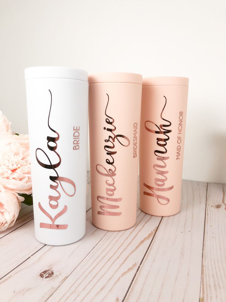 three pink and white coffee mugs sitting on top of a wooden table next to flowers