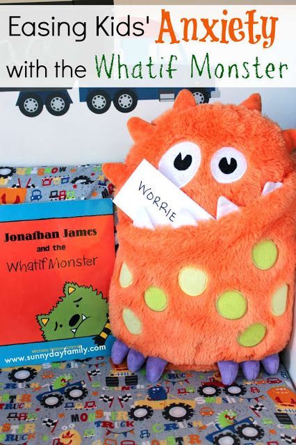 an orange monster stuffed animal sitting on top of a bed next to a bookcase