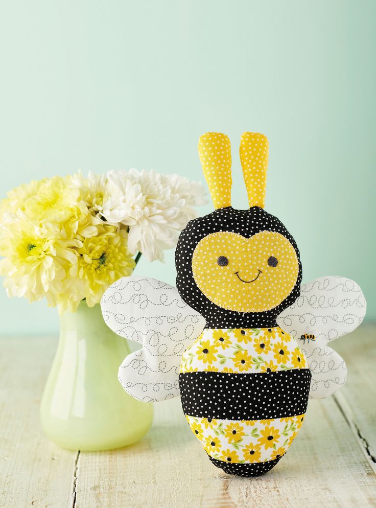 a yellow and black bee sitting next to a vase with flowers