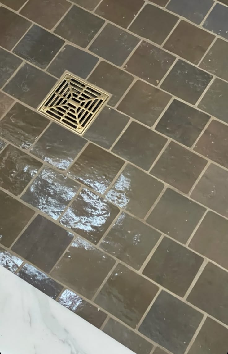 a tile shower with a drain in the middle and a grate on the floor