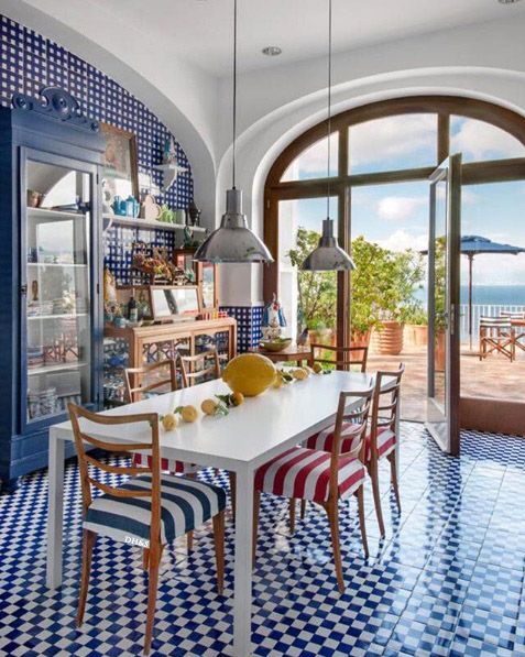 a dining room with blue and white checkered flooring next to an open door