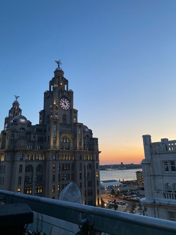 a large building with a clock on it's face at sunset or dawn in the city