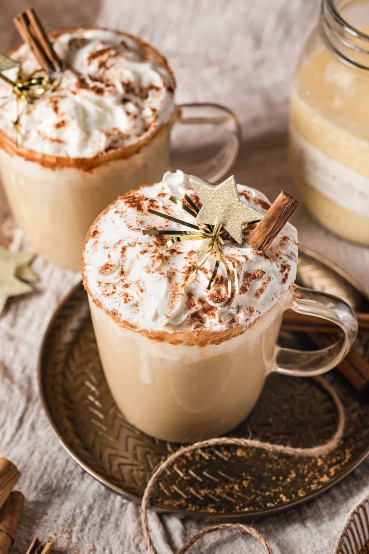 two hot chocolate drinks on a plate with cinnamon sticks and star anisette decorations