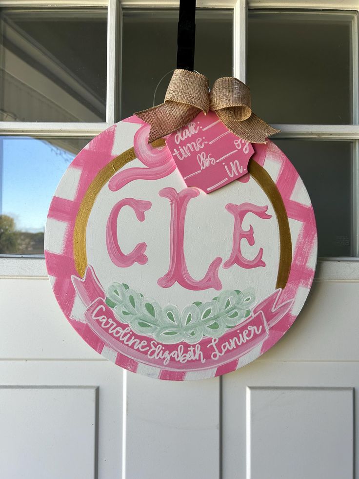 a pink and white door hanger with the word cle painted on it's front