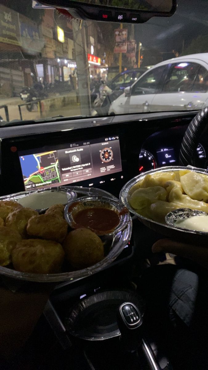 two plates of food are sitting on the dashboard of a car as someone drives by