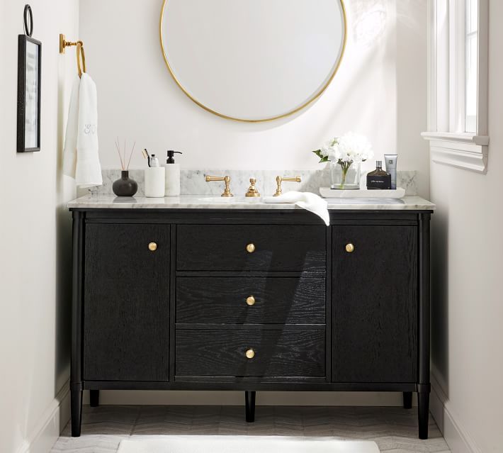 a bathroom vanity with two sinks and a round mirror on the wall above it, in front of a window