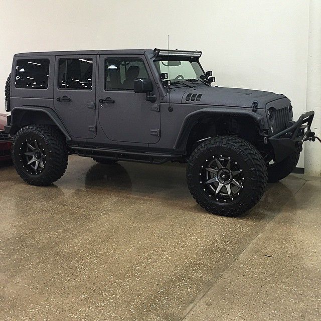 a gray jeep is parked in a garage