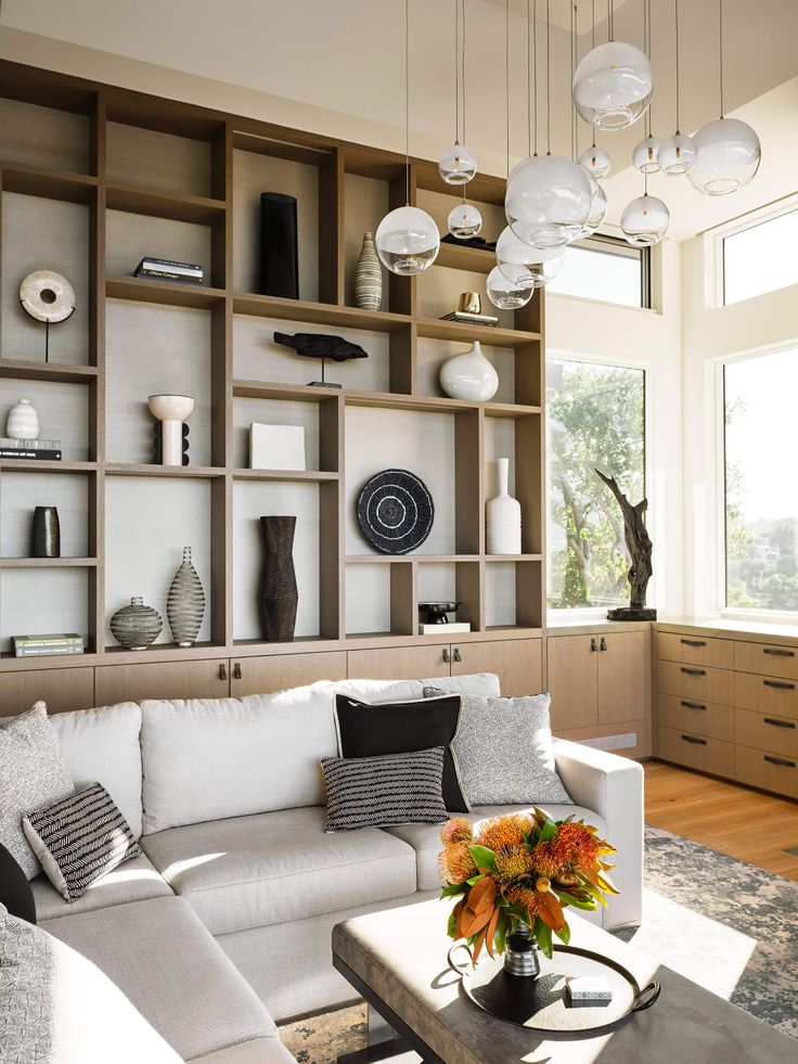 a living room filled with white furniture and lots of shelves on the wall behind it