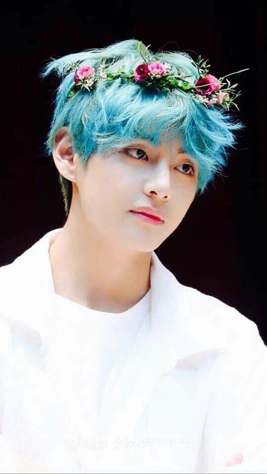 a young man with blue hair and flowers in his hair is wearing a white shirt