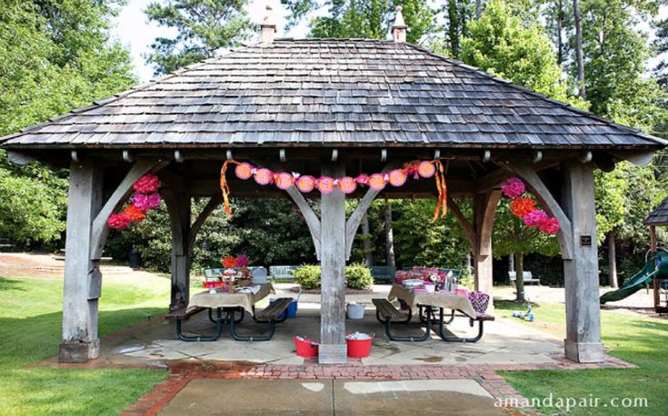 a wooden gazebo with tables and chairs under it