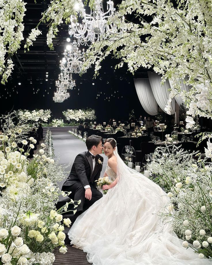 a bride and groom pose for a photo in front of white flowers at their wedding