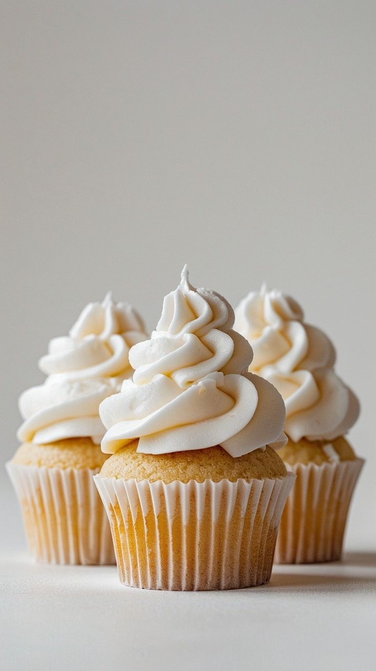 three cupcakes with white frosting sitting on top of each other in front of a white background