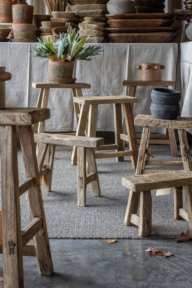 several wooden chairs and stools in a room