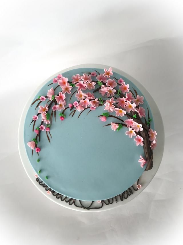 a cake decorated with pink flowers on top of a blue plate, sitting on a white surface