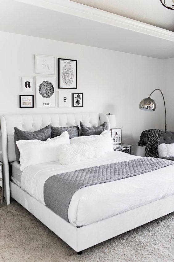 a bedroom with white and gray bedding and pictures on the wall