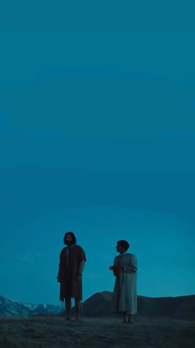 two people standing on top of a hill at night