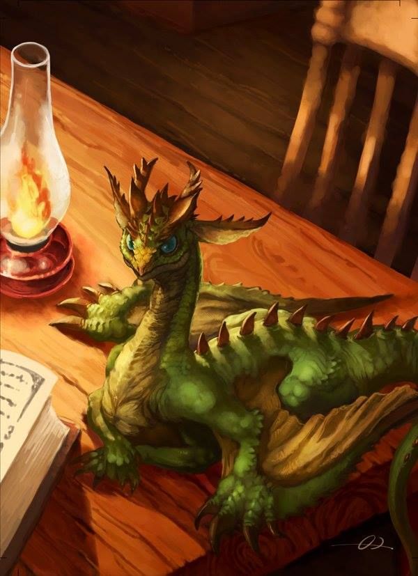 a green dragon sitting on top of a wooden table next to a book and lamp