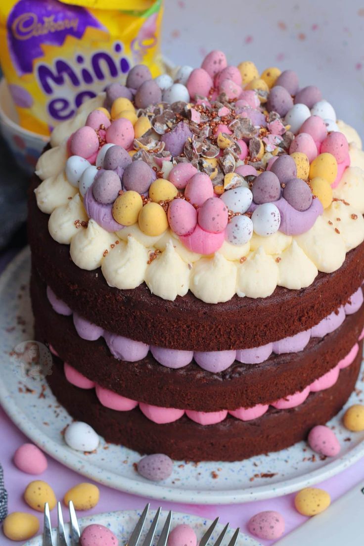 a chocolate cake with white frosting and colorful candies on top, surrounded by mini eggs