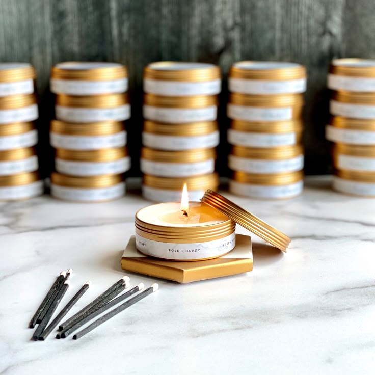 a candle sits on top of several stacks of gold and white plates with candles in them