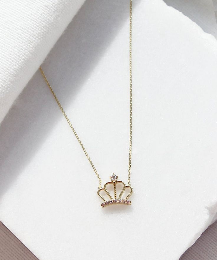 A small dainty crown hanging on a simple solid gold chain. This is a unique piece for celebrating yourself or your loved ones. It is perfect for everyday wear as it made of solid gold and won't tarnish. We promise that this necklace will be a piece you cherish forever. #aesthetic #crown #14K #gold # necklace #queen #princess #8K #bridal #cute #gift #anniversary #royalty #royal #jewellery #jewelry #jewel #minimalist Gold Crown Jewelry With Diamond Accents, Gold Diamond Jewelry With Crown Design, Gold Diamond Crown Jewelry, Fine Jewelry Yellow Gold Crown Shaped, 14k Gold Crown Jewelry With Diamond Accents, Gold Cubic Zirconia Teardrop Crown Jewelry, Elegant Crown Design Necklace For Wedding, Elegant Crown Pendant Jewelry, Elegant Crown Design Necklace For Gift