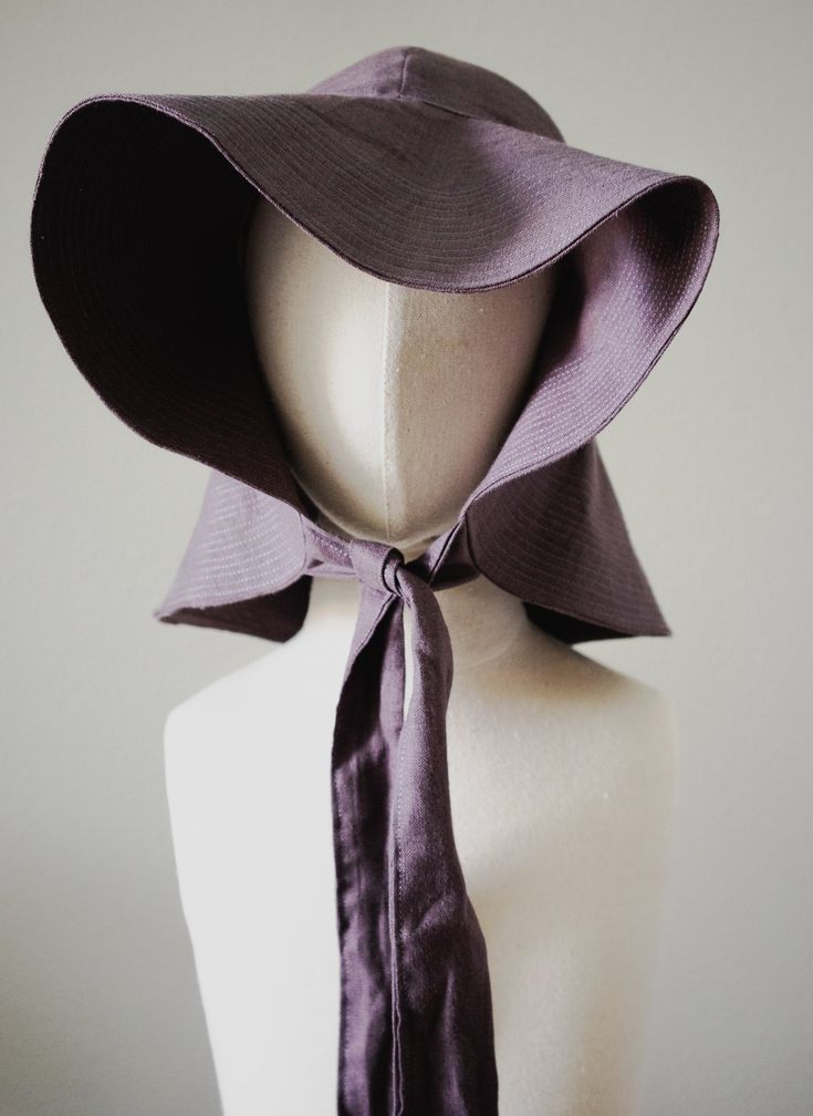 a white mannequin with a purple hat and tie on it's head