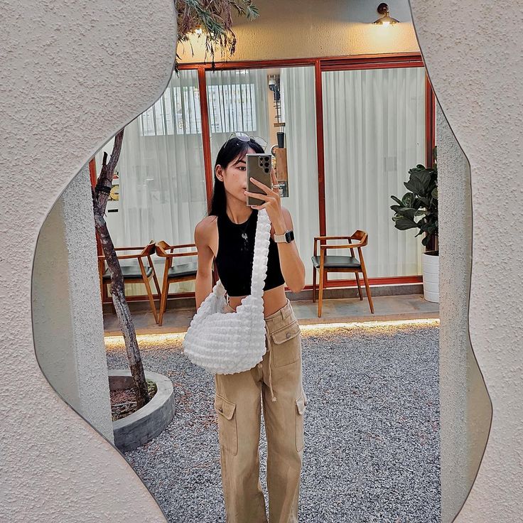 a woman taking a selfie with her cell phone in front of a mirror on the ground