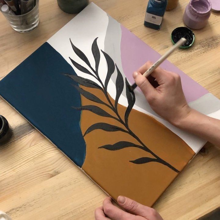 a person is using a brush to paint on a piece of paper that looks like a plant