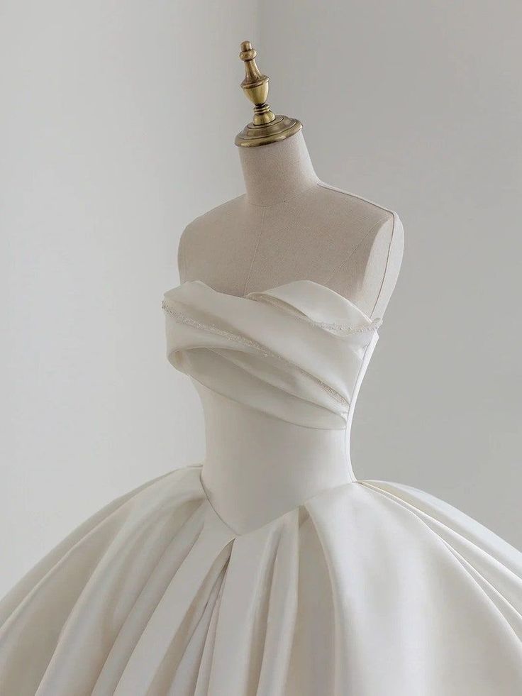 a white wedding dress on a mannequin with a gold headpiece in the background