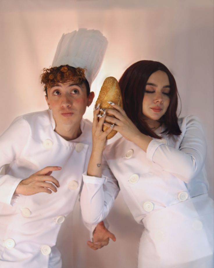 two people dressed in white are posing for a photo while one holds a sandwich up to his face