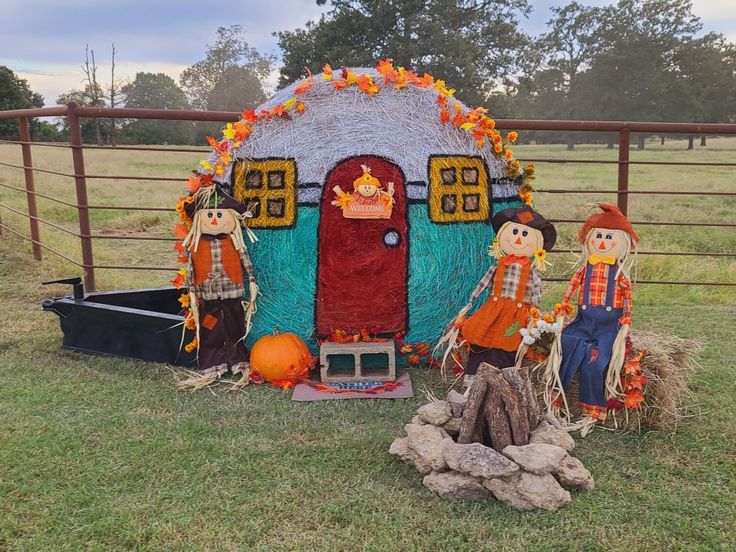 a group of scarecrows sitting in front of a fake house on the grass