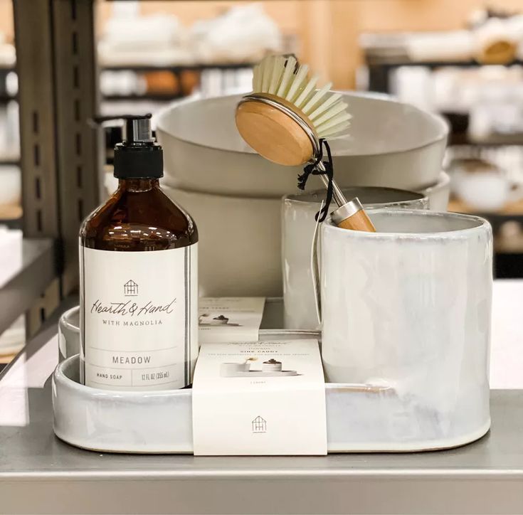 a white cup sitting on top of a counter next to a brush and soap dispenser