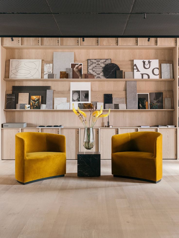 two yellow chairs sitting next to each other in front of a book shelf filled with books