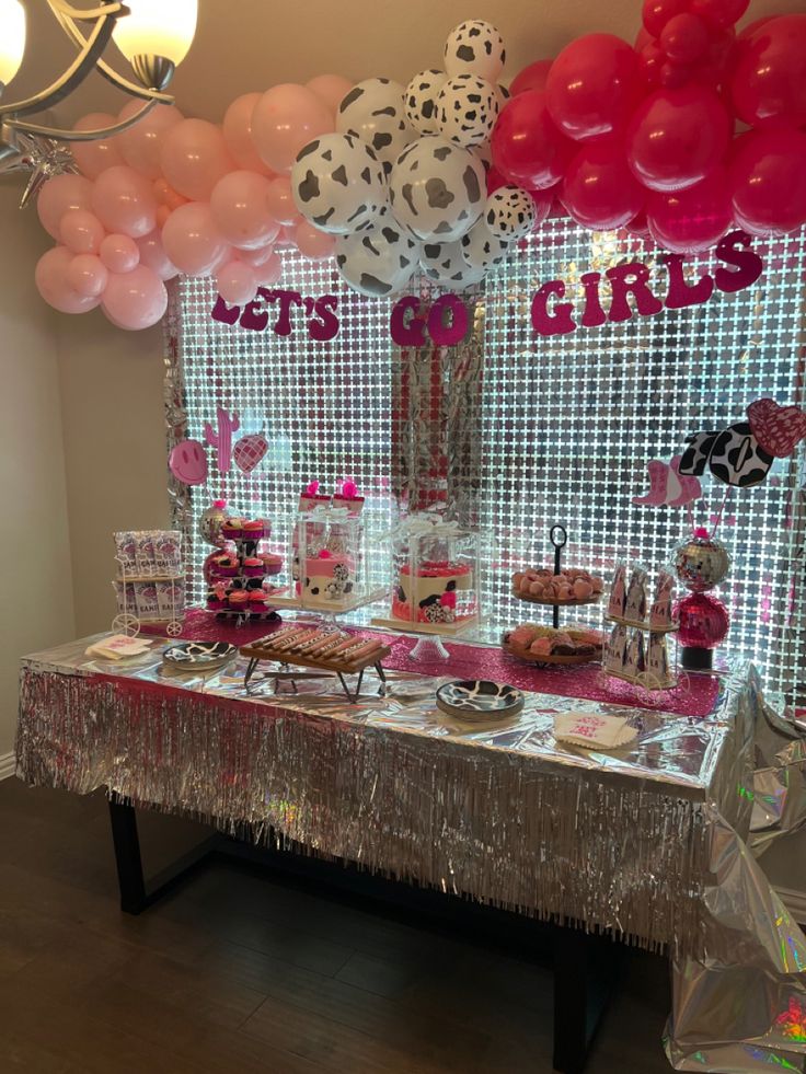 a table topped with lots of pink and white balloons