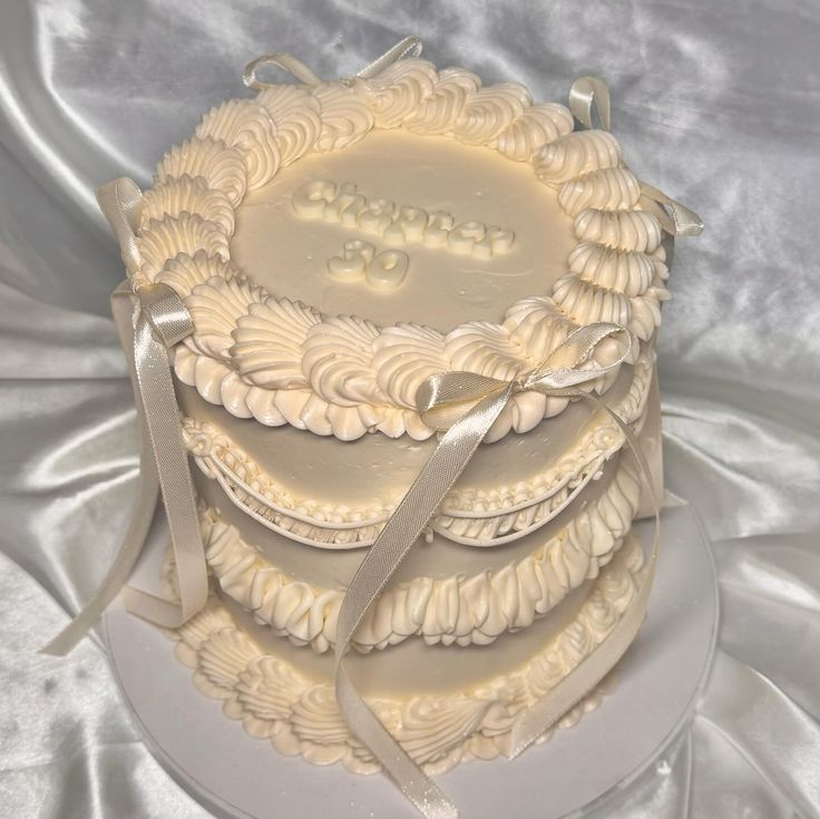 a wedding cake with white frosting and ribbons