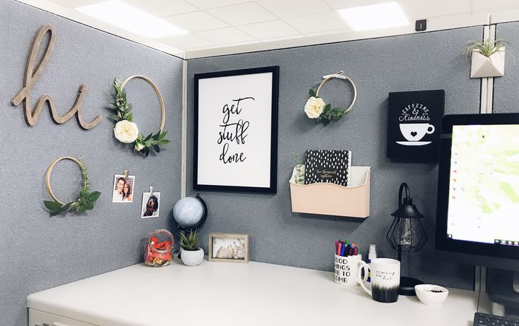 an office cubicle with flowers and pictures on the wall, including a computer monitor