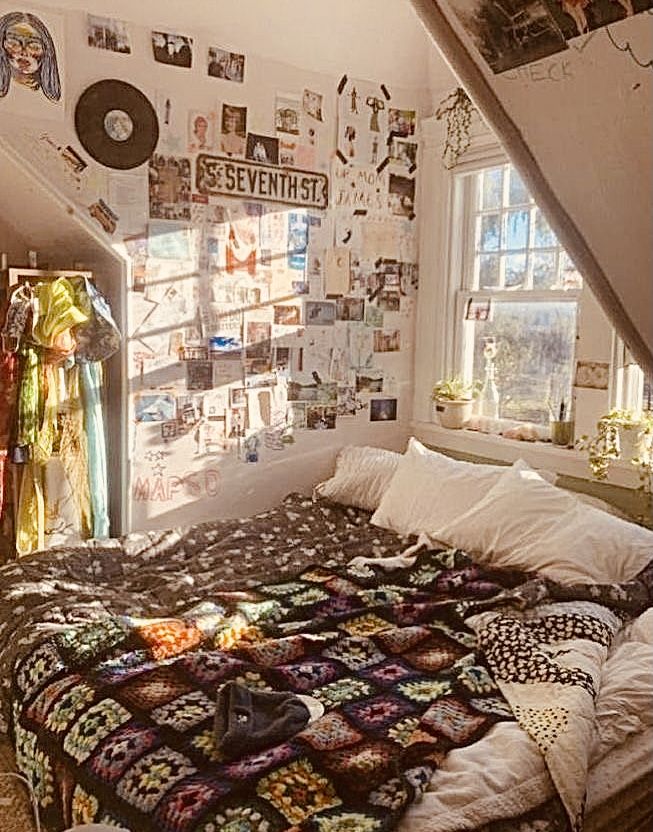 a bed sitting under a window in a bedroom next to a wall with pictures on it