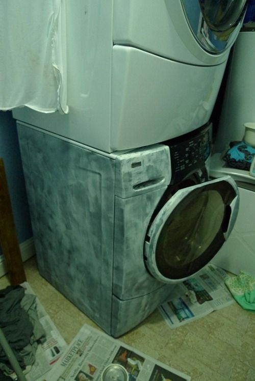 a washer and dryer sitting next to each other in a room with newspapers on the floor